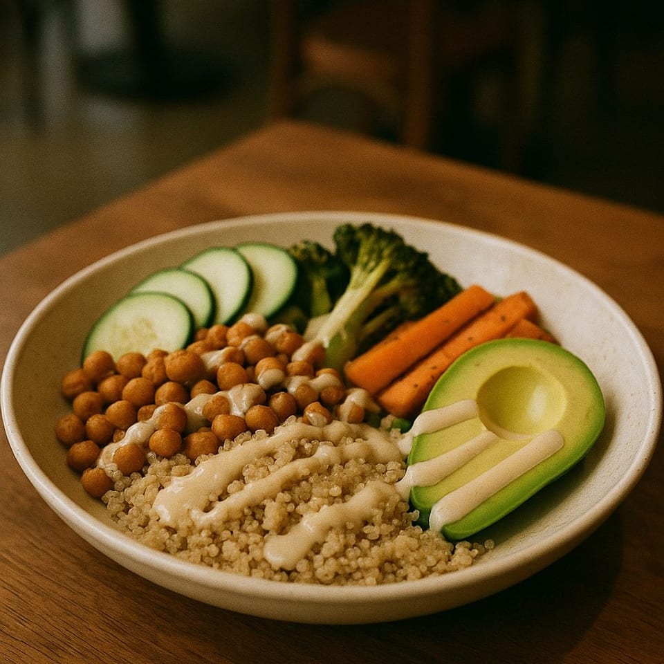 Vicki's quinoa bowl with chickpeas, avocado, broccoli, carrots, and cucumber, drizzled with sauce.